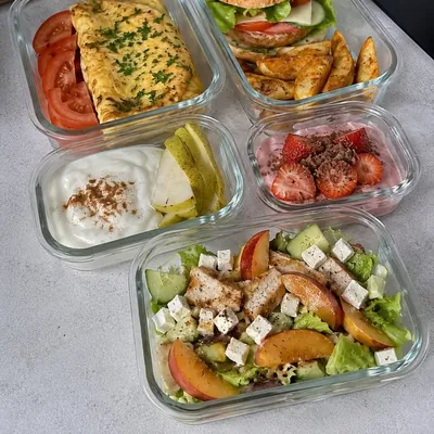 Cinq boîtes repas préparés : omelette, burger, yaourt aux poires, yaourt aux fraises et salade de poulet